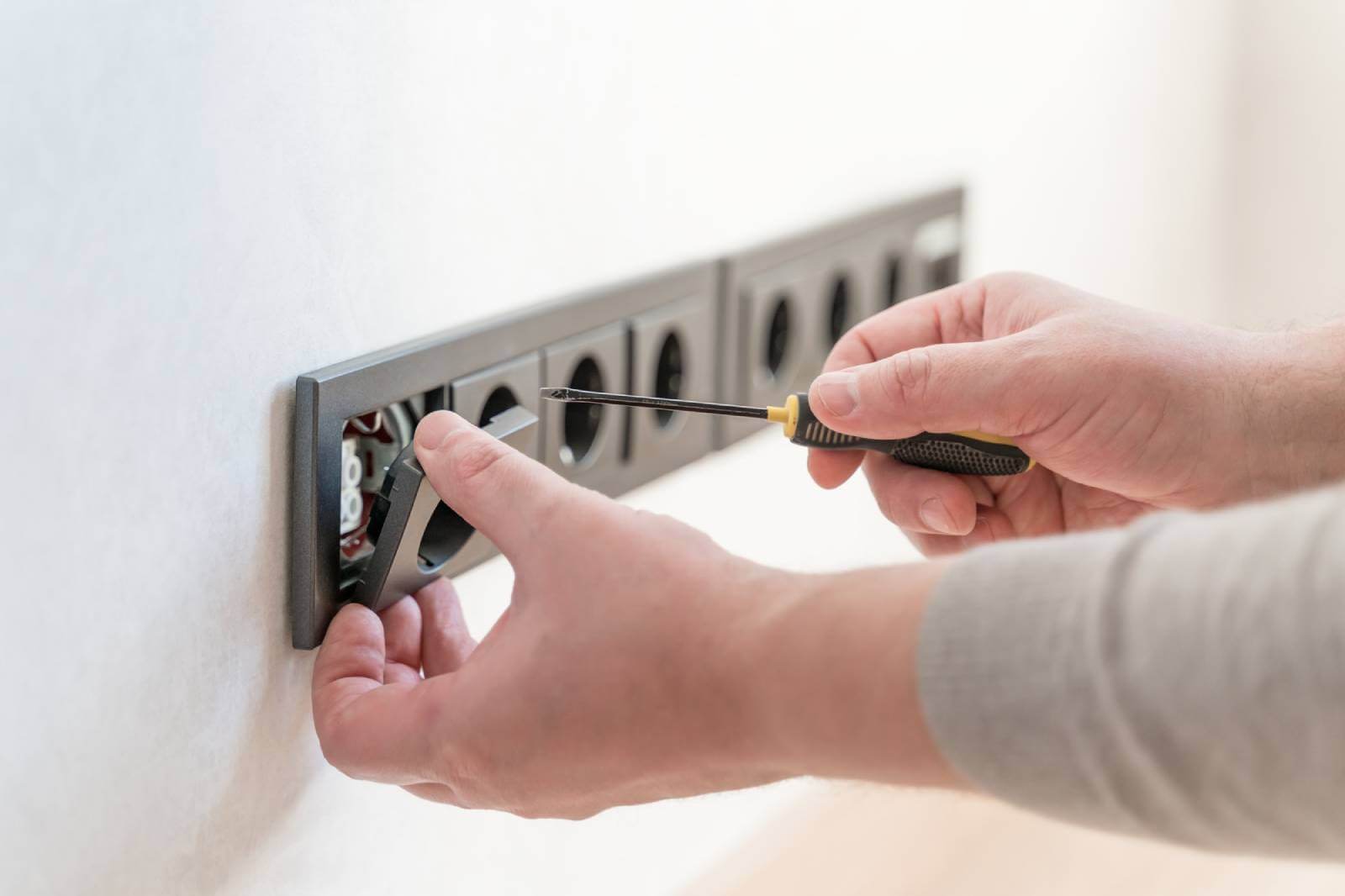 ACS worker with black screwdriver fixing black outlet